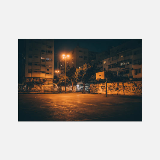 A rectangular wall art print showing a nighttime urban court scene with glowing streetlights, apartment buildings, trees, and graffiti-covered walls, centered on a light gray background.