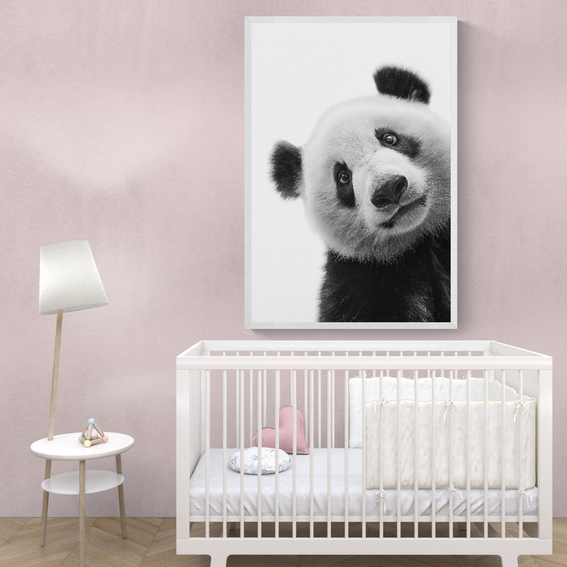 Nursery with a white crib and a large framed black and white shy panda picture on the wall.