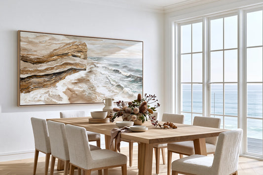 Large abstract coastal artwork above dining table, ocean cliffs in warm tan and white tones, oak frame, calm coastal dining room, FRAMZE wall art