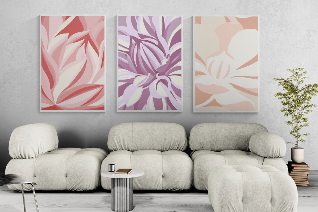 Three framed abstract floral wall art prints in pink, purple and orange above a cream sofa in a bright neutral living room