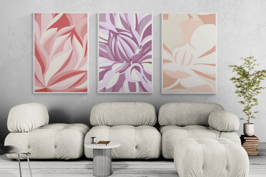 Three framed abstract floral wall art prints in pink, purple and orange above a cream sofa in a bright neutral living room