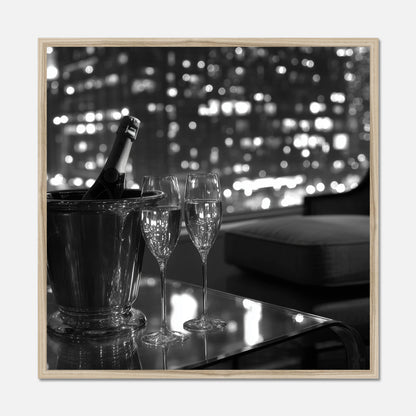 Natural oak framed wall art of two champagne glasses and a bottle in an ice bucket on a table with a cityscape in the background.
