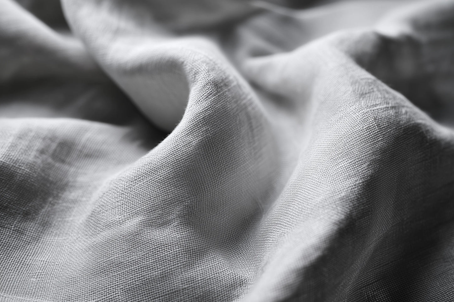 Close-up of draped light gray fabric with soft folds and visible woven texture.