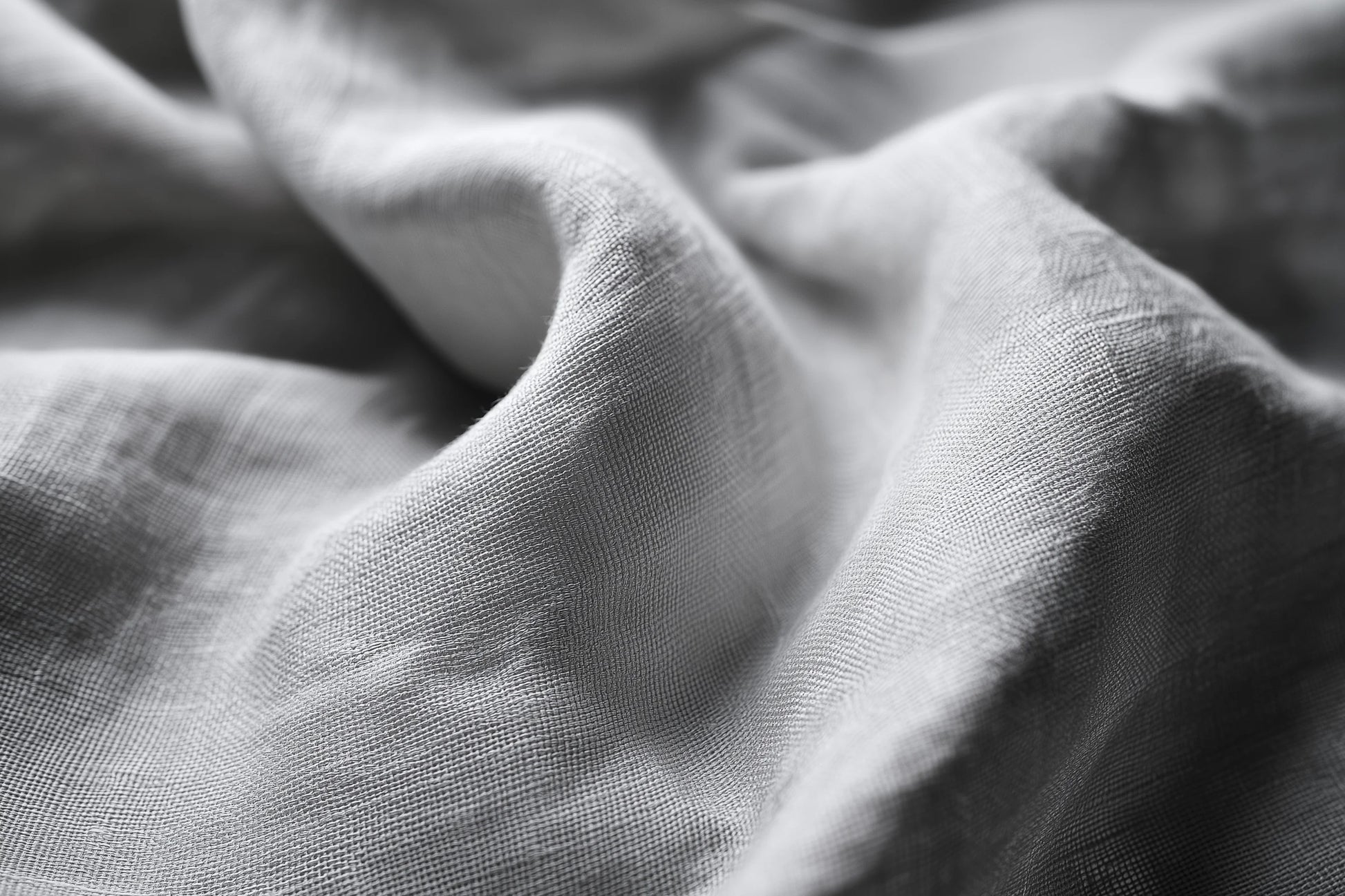 Close-up of draped light gray fabric with soft folds and visible woven texture.
