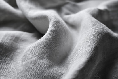 Close-up of draped light gray fabric with soft folds and visible woven texture.