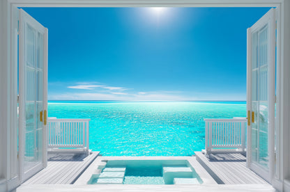 Window seat view out of two bi-fold doors, turquoise sea, a plunge pool in the deck and white fenceing