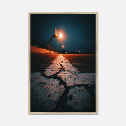 Framed photograph of a street scene with a light post and wet pavement at night.