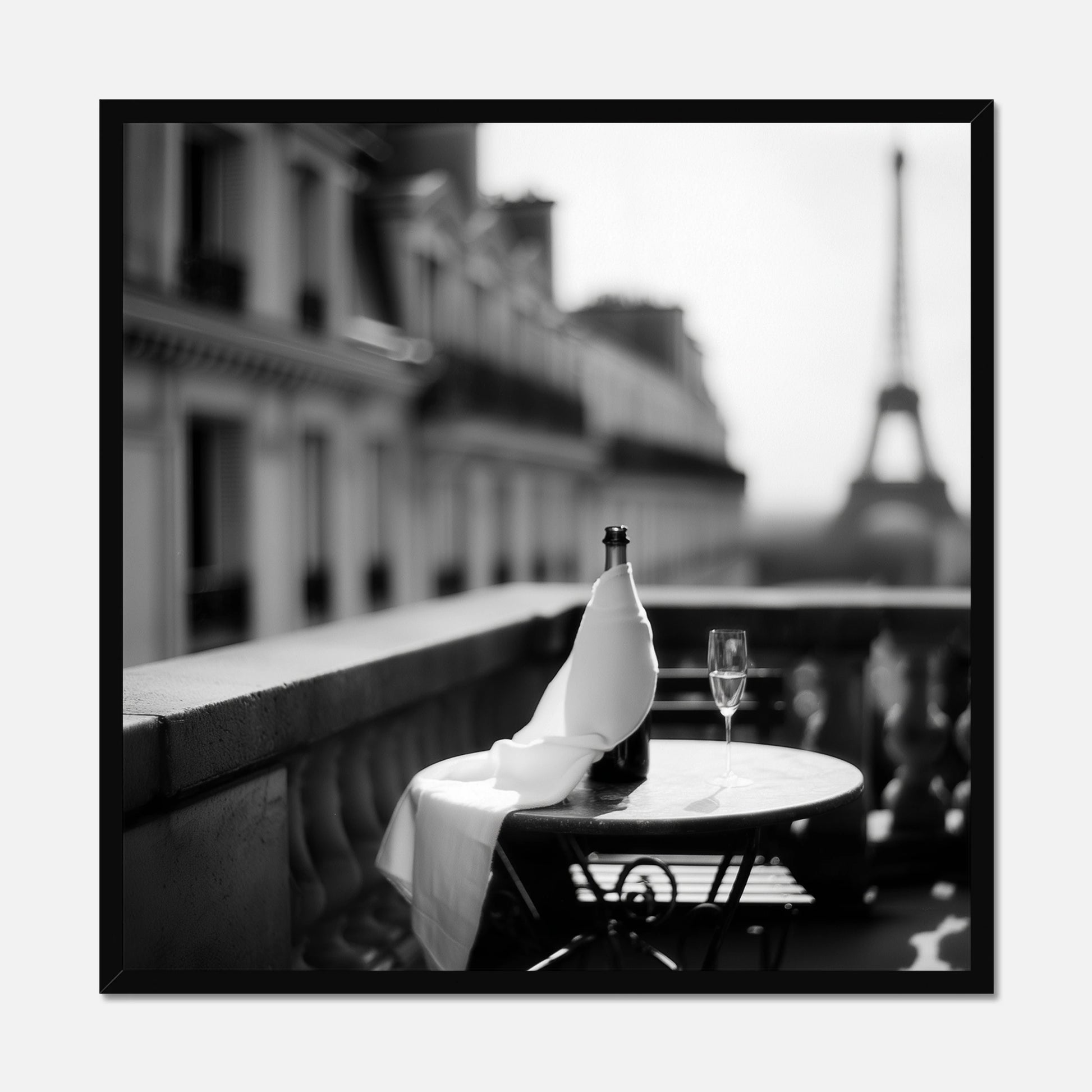 Black framed bottle and wine glass on a table with the Eiffel Tower in the background