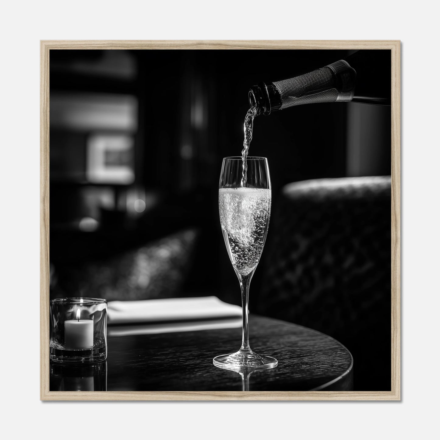 Natural oak framed print of champagne being poured into a glass on a table with a blurred background
