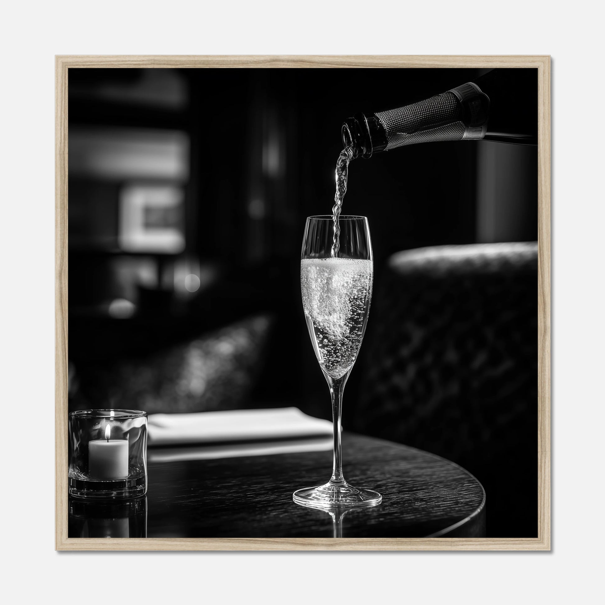 Natural oak framed print of champagne being poured into a glass on a table with a blurred background