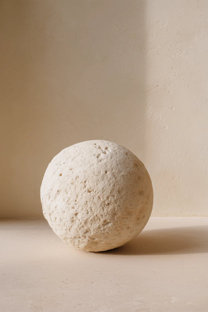 A pumice sphere centered in a beige room