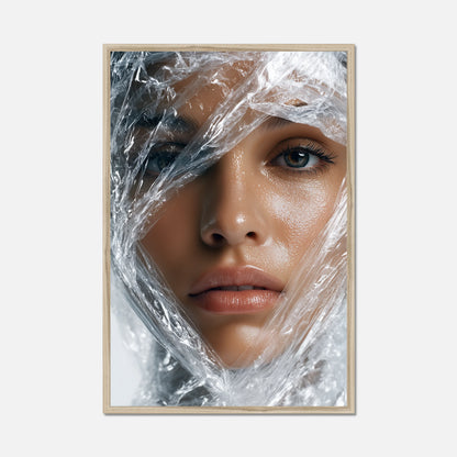 Framed artwork of a woman's face partially covered by clear plastic wrap on a white background