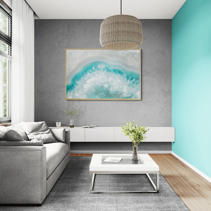 A modern living room featuring the best framed abstract wave art print with turquoise and white tones hanging on a textured gray wall above a white media console and gray sofa.
