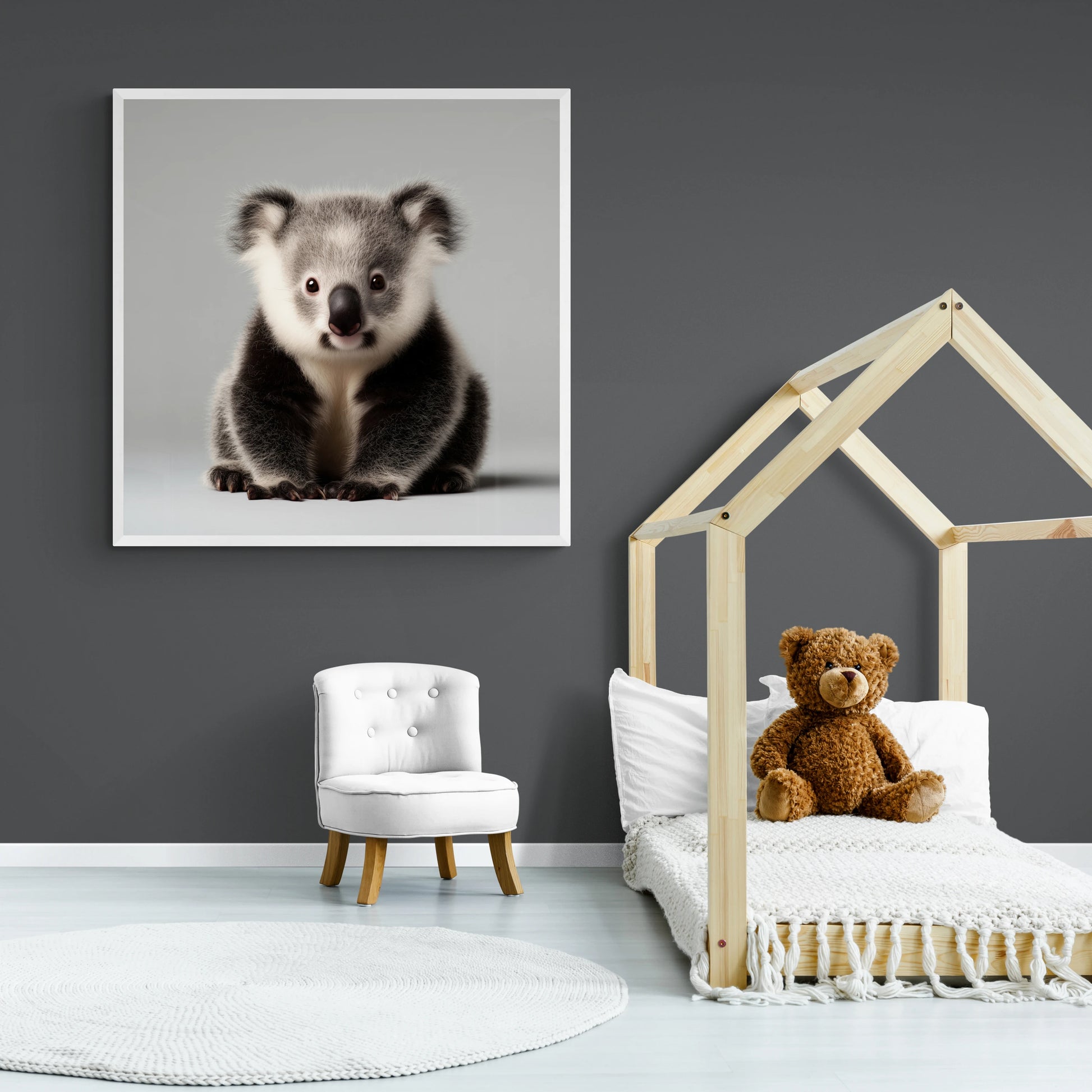 Children's room with a framed picture of a koala, a teddy bear on a bed, and a small white chair.