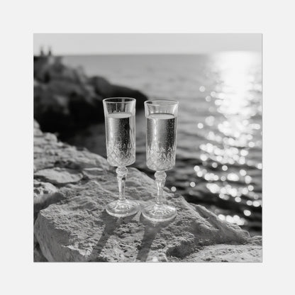 Two champagne glasses on a rock by the water with a wooden frame.