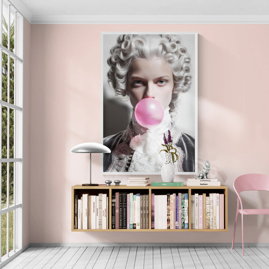 The best large framed wall art print hangs on a pale pink wall above a floating bookshelf in a styled room. The artwork shows a close-up portrait of a person with powdered white hair blowing a pink bubblegum bubble.