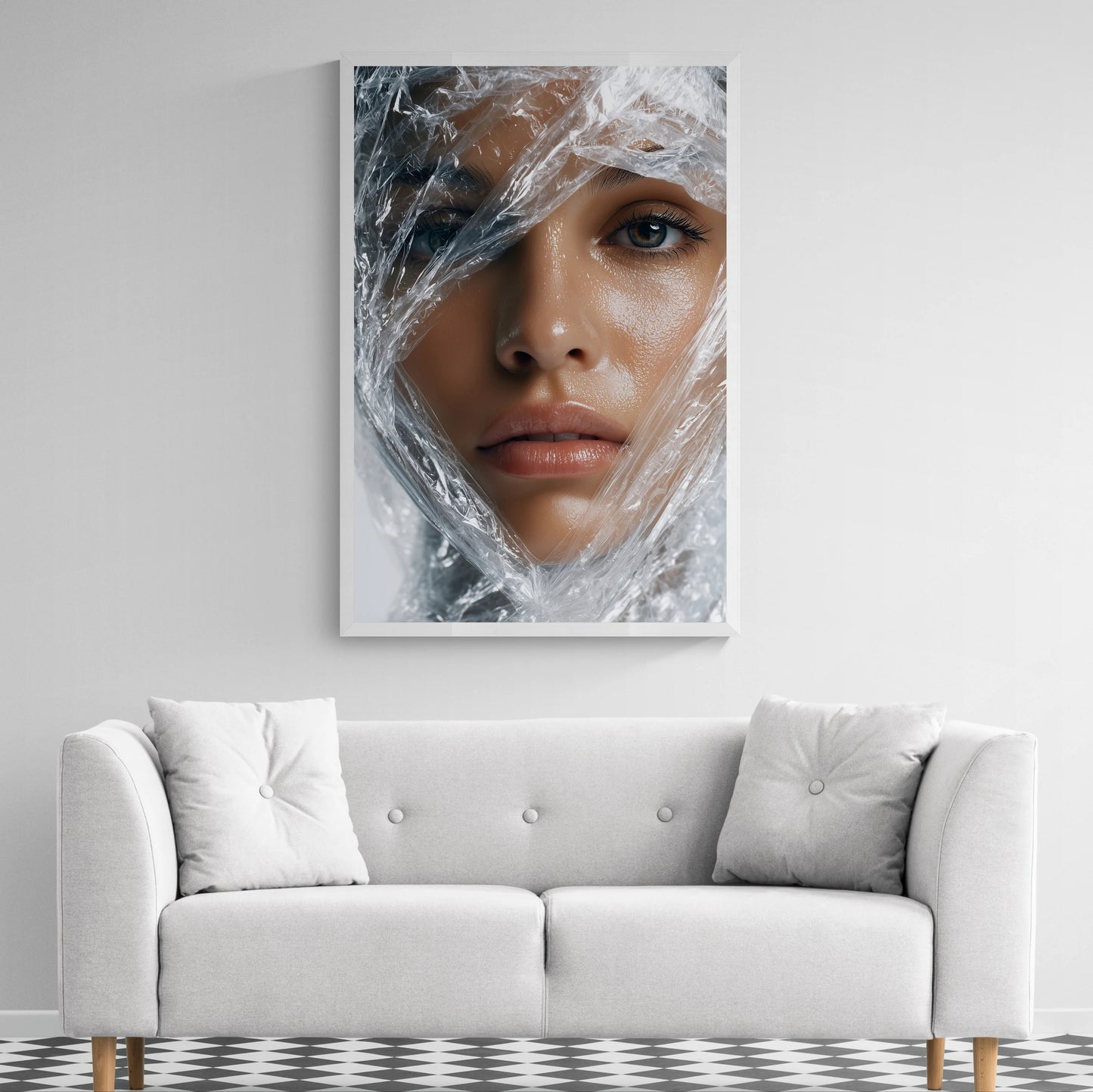 A framed wall art print showing a close-up portrait of a woman wrapped in crinkled transparent plastic, displayed above a light gray sofa in a modern room.