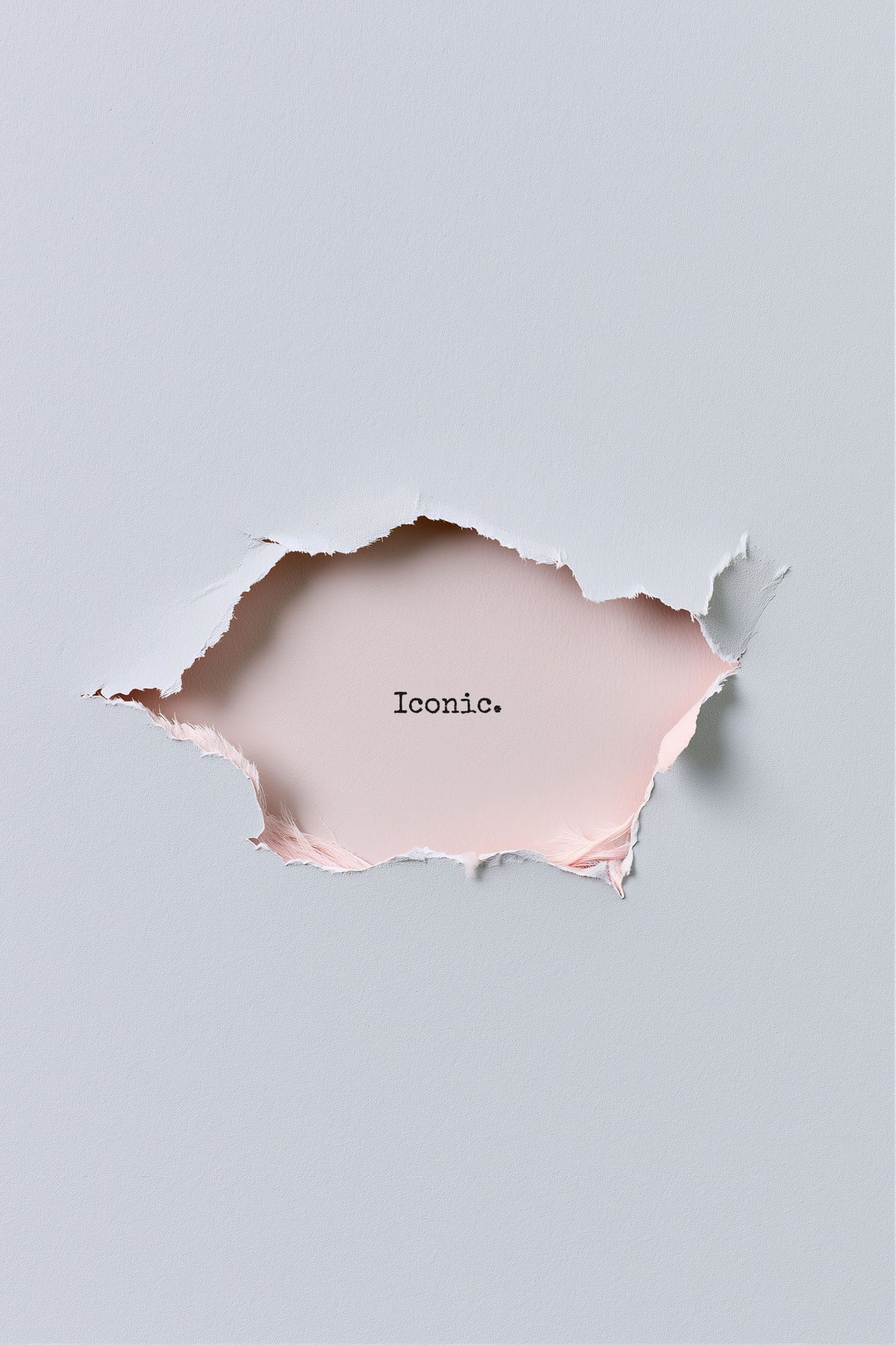 A minimalist art print featuring a torn paper hole in the center of a light gray background, revealing a pale pink paper layer underneath with the word 'Iconic.' printed in black typewriter font.