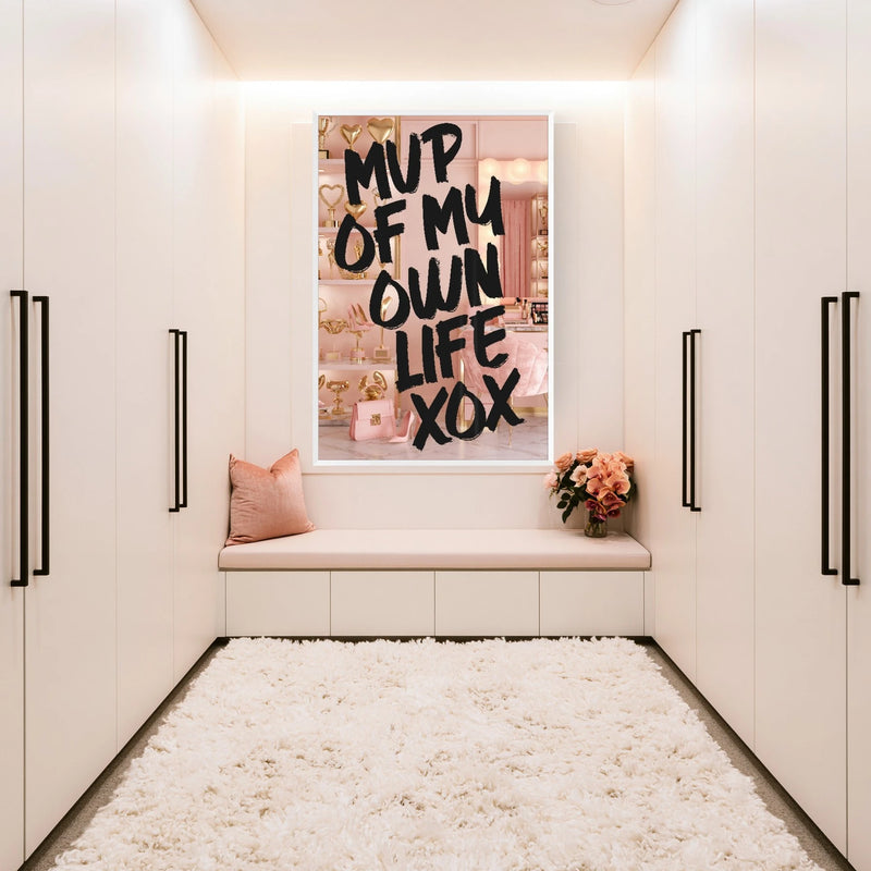 A framed wall art print with the text 'MVP OF MY OWN LIFE XOX' in black lettering, displayed above a blush pink bench in a modern, minimalist white room with a fluffy white rug.